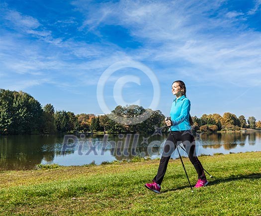 Nordic walking adventure and exercising concept - woman hiking withnordic walking poles in park