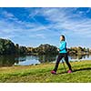 Nordic walking adventure and exercising concept - woman hiking withnordic walking poles in park