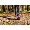 Nordic walking adventure and exercising concept - woman hiking, legs and nordic walking poles in autumn nature