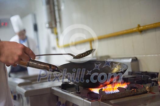 chef in hotel kitchen prepare vegetable  food with fire