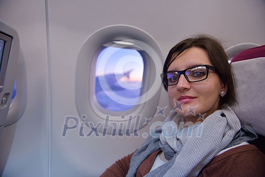 happy young  tourist  woman is sitting in the airplane looking windov and travel to summer vacation