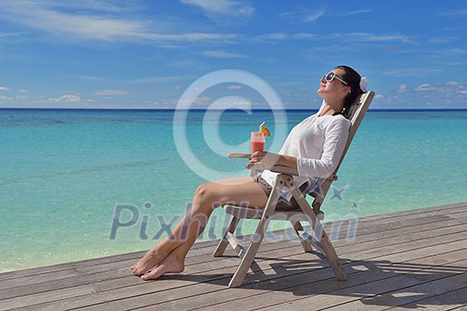 Beautiful young woman in bikini lying on a deckchair with a drink by the sea Beautiful young woman in bikini lying on a deckchair with a drink by the sea