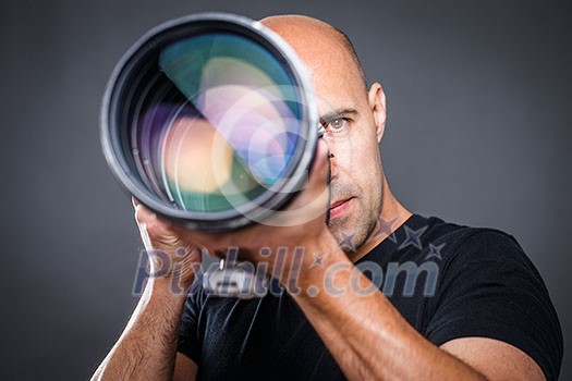 Young, pro male photographer in his studio during a photo shoot (color toned image; shallow DOF)