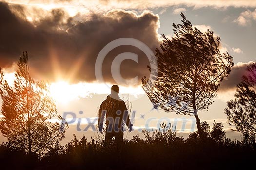 Adventurous man observing a lovely sunset in nature, alone, standing proudly Adventurous man observing a lovely sunset in nature, alone, standing proudly