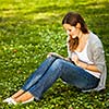 Young woman using her tablet computer while relaxing outdoors in a park on a lovely spring day