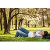 Young woman using her tablet computer while relaxing outdoors in a park on a lovely spring day