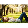 Young woman using her tablet computer while relaxing outdoors in a park on a lovely spring day