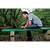 one young businessman working on laptop outdoor with green nature in background