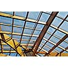 modern home roof wood roof construction with many windows blue sky and green palm leafs
