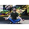young happy man in urban enviroment practicing and meditating yoga in lotus position 