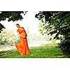 beautiful young happy pregnant woman outdoor in bright nature in orange dress