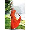 beautiful young happy pregnant woman outdoor in bright nature in orange dress