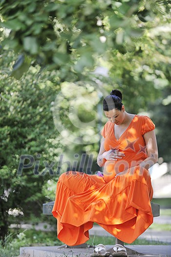 beautiful young happy pregnant woman outdoor in bright nature in orange dress beautiful young happy pregnant woman outdoor in bright nature in orange dress