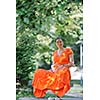 beautiful young happy pregnant woman outdoor in bright nature in orange dress