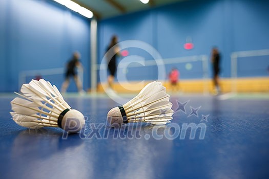 badminton - badminton courts with players competing; shuttlecocks in the foreground (shallow DOF; color toned image)
