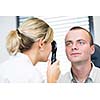 Optometry concept - handsome young man having her eyes examined by an eye doctor