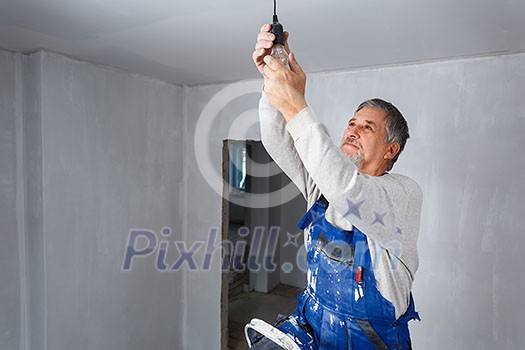 Senior man installing a bulb in a freshly renovated appartment Senior man installing a bulb in a freshly renovated appartment