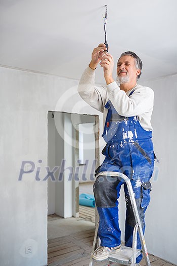 Senior man installing a bulb in a freshly renovated appartment Senior man installing a bulb in a freshly renovated appartment