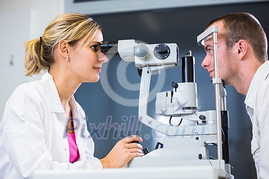Optometry concept - handsome young man having his eyes examined by an eye doctor (color toned image; shallow DOF)
