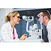 Optometry concept - handsome young man having his eyes examined by an eye doctor (color toned image; shallow DOF)