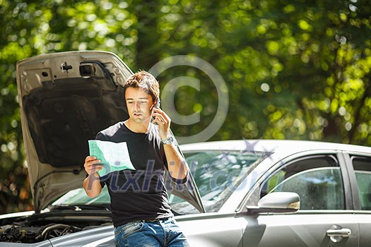 Handsome young man calling for assistance with his car broken down by the roadside