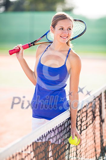 Portrait of a pretty, young tennis player  on  a court on a lovely summer day
