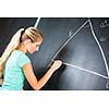 Pretty young elementary school/college teacher writing on the chalkboard/blackboa rd during a math class (color toned image; shallow DOF)