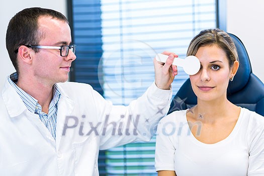 Optometry concept - pretty young woman having her eyes examined by an eye doctor