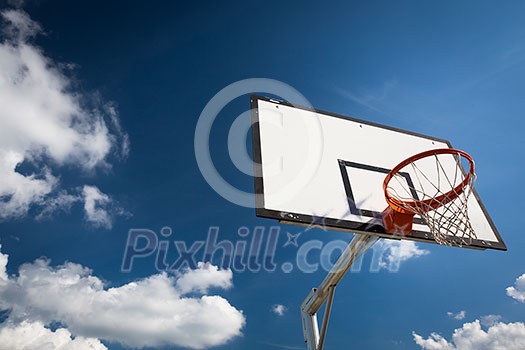 Basketball hoop against  lovely blue summer sky with some fluffy white clouds