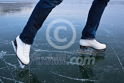 Young woman ice skating outdoors on a pond on a freezing winter day