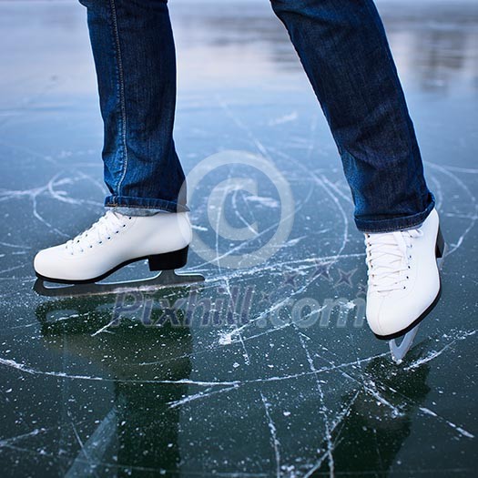 Young woman ice skating outdoors on a pond on a freezing winter day