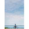 Background for poster or advertisment pertaining to cycling/sport/outdoor activities - female cyclist during a halt on a bridge against blue sky (color toned image)