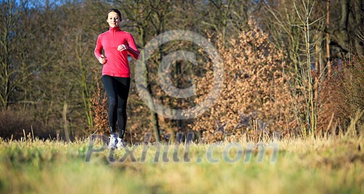 Young woman running outdoors on a lovely sunny winter/fall day (motion blurred image)