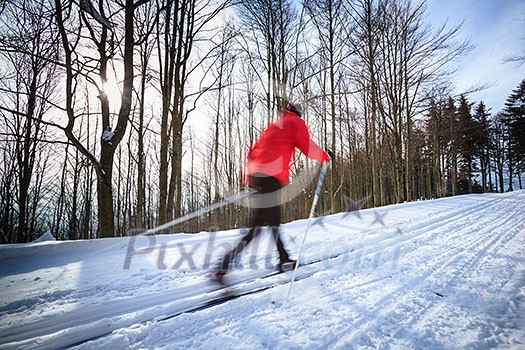 Cross-country skiing: young man cross-country skiing on a lovely sunny winter day (motion blur technique is used to convey movement)