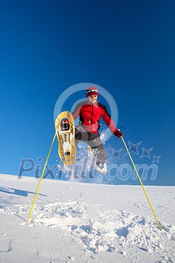 Young man having fun while snowshoeing outdoors on a lovely snowy winter day