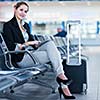 Young female passenger at the airport, using her tablet computer while waiting for her flight (color toned image)