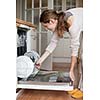 Housework: young woman putting dishes in the dishwasher