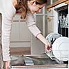 Housework: young woman putting dishes in the dishwasher