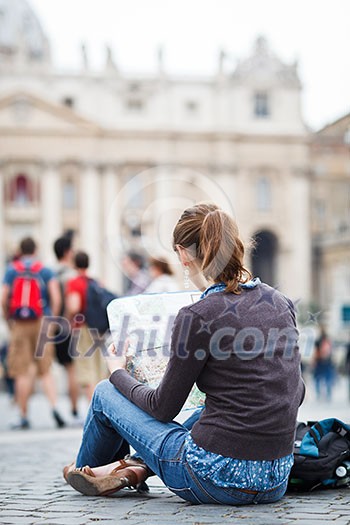 Pretty young female tourist studying a map at St. Peter's square in the Vatican City in Rome