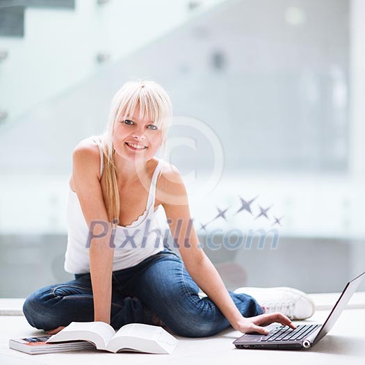 On campus - pretty female student with laptop and books working before class on her assignment/homework (color toned image) On campus - pretty female student with laptop and books working before class on her assignment/homework (color toned image)