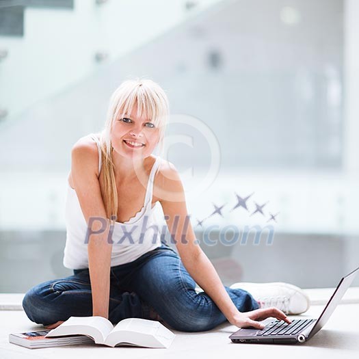 On campus - pretty female student with laptop and books working before class on her assignment/homework  (color toned image)