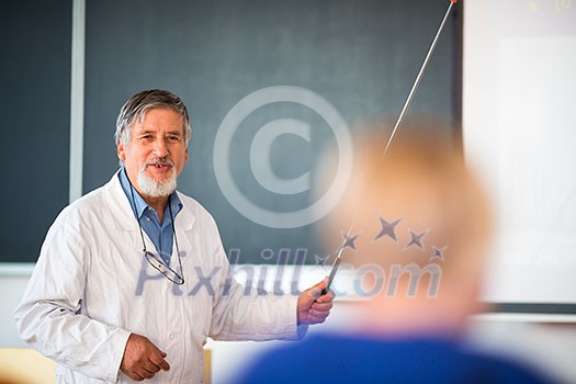 Senior chemistry professor giving a lecture in front of classroom full of students (shallow DOF; color toned image)