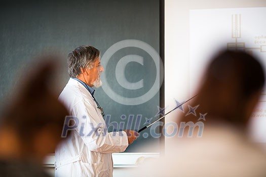 Senior chemistry professor giving a lecture in front of classroom full of students (shallow DOF; color toned image)