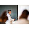 Senior chemistry professor giving a lecture in front of classroom full of students (shallow DOF; color toned image)