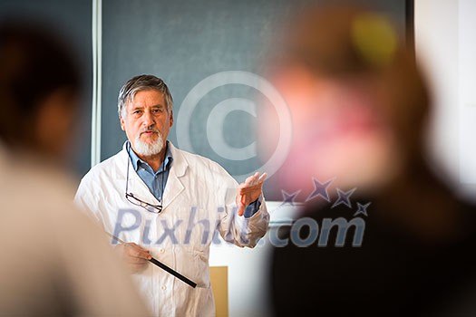 Senior chemistry professor giving a lecture in front of classroom full of students (shallow DOF; color toned image) Senior chemistry professor giving a lecture in front of classroom full of students (shallow DOF; color toned image)