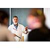 Senior chemistry professor giving a lecture in front of classroom full of students (shallow DOF; color toned image)