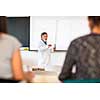 Senior chemistry professor giving a lecture in front of classroom full of students (shallow DOF; color toned image)