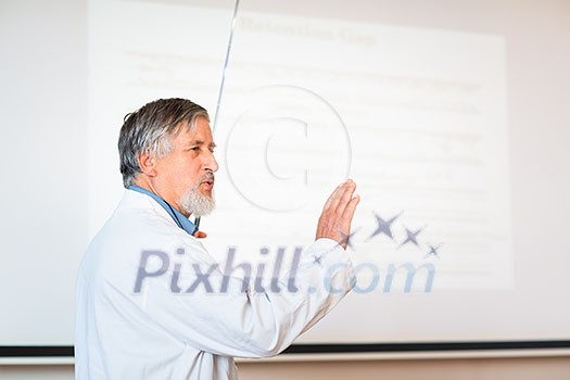 Senior chemistry professor giving a lecture in front of classroom full of students (shallow DOF; color toned image)