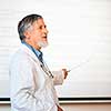 Senior chemistry professor giving a lecture in front of classroom full of students (shallow DOF; color toned image)