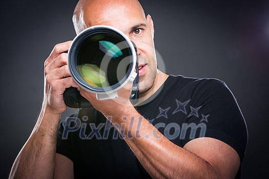 Young, pro male photographer in his studio during a photo shoot (color toned image; shallow DOF) Young, pro male photographer in his studio during a photo shoot (color toned image; shallow DOF)